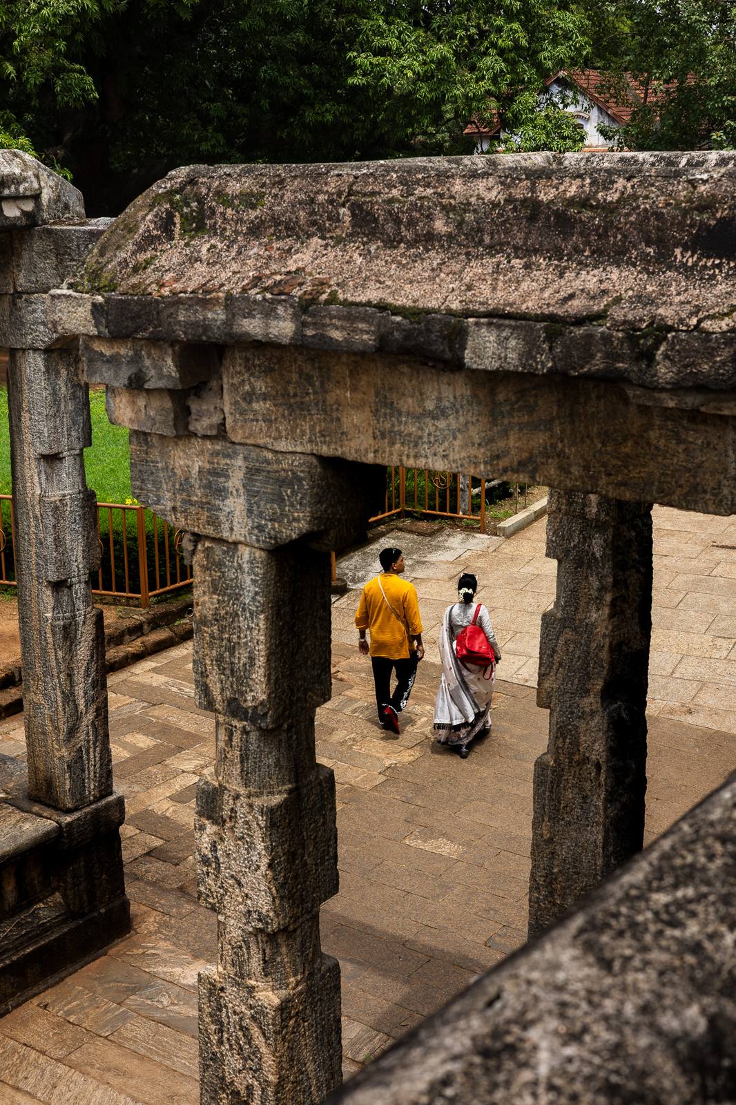 Couple walking through carved stone pillars in Kerala
