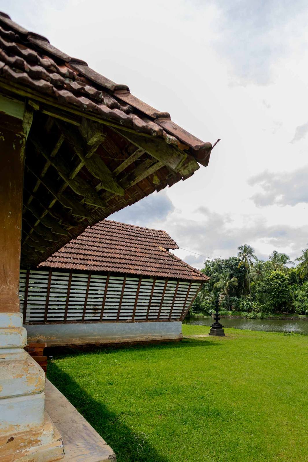 A traditional tiled-roof heritage home beside a Kerala pond
